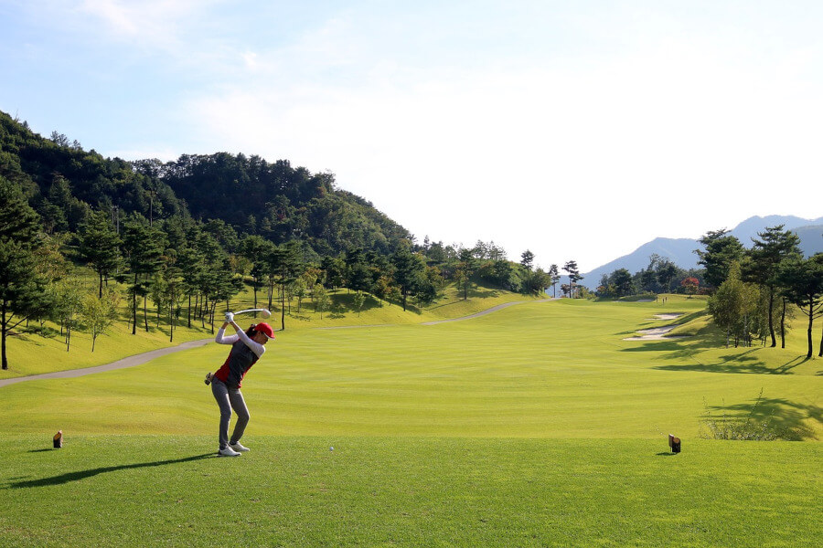woman hitting golf ball with driver